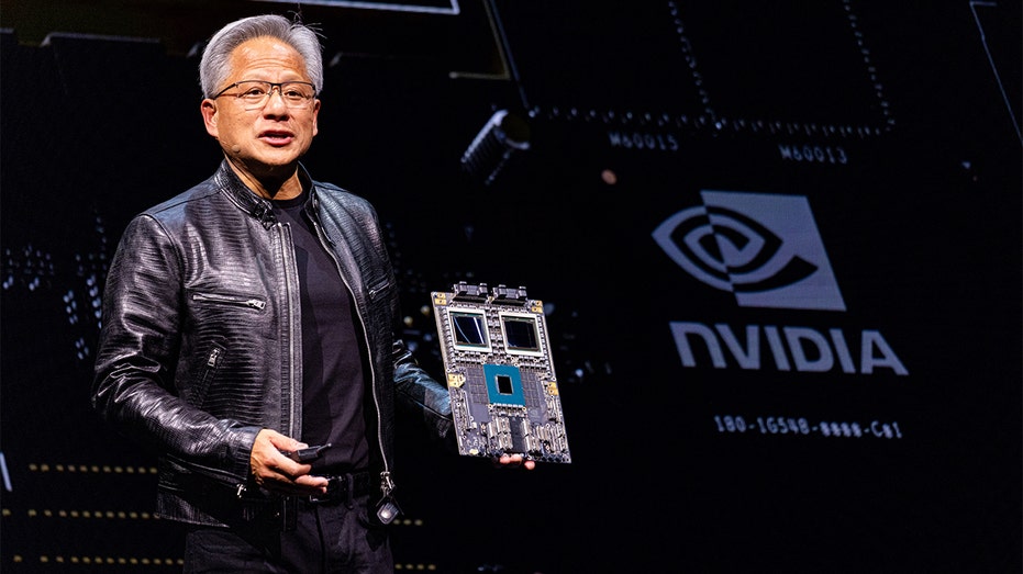 Nvidia launches massive AI push with major partnerships across multiple industries 6 Huang holding up a circuit board while giving a talk.