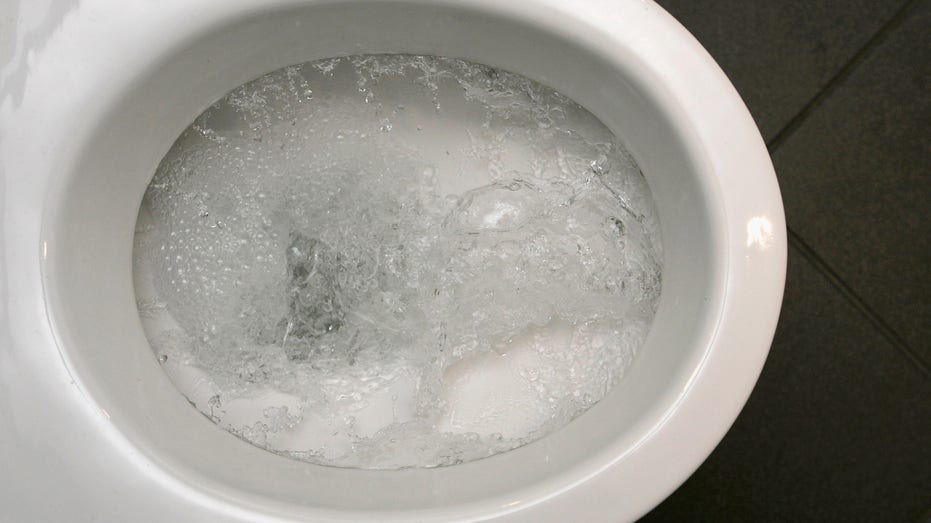Toilet bowl with water flushing.